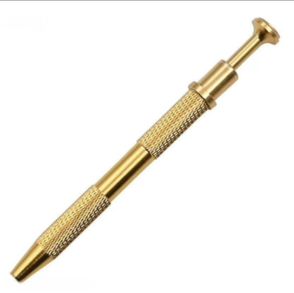 Gold-coloured four-prong pickup tool with knurled grip and retractable plunger shown on white.
