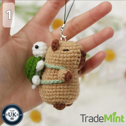 Small crocheted capybara and turtle keyring held in a hand with the loop and clasp visible.