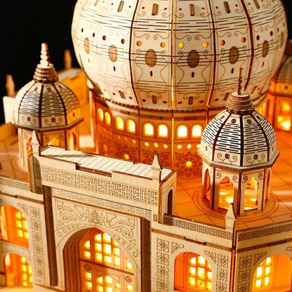 Close-up of illuminated wooden Taj Mahal model showing domes, arches and warm window lights.