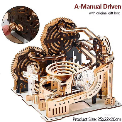 Manual-driven wooden marble run model with gear wheels and spiral track, shown with a hand winding its mechanism.