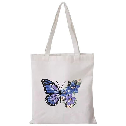 White canvas shoulder tote with blue butterfly and purple floral embroidered design.
