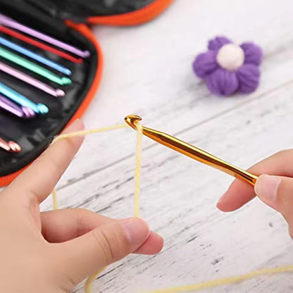 Hands using a gold-coloured aluminium crochet hook with yellow yarn beside an open orange tool case.