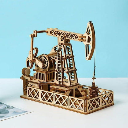 Angled view of mechanical wooden oil pumpjack puzzle showing the ladder, lattice frame and pump counterweights.