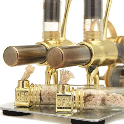 Close-up of two gold Stirling engine cylinder ends above woven fuel wicks and brass holders.