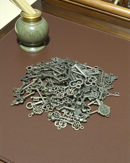 Pile of antique bronze skeleton key charms with heart, flower and filigree designs on a brown tabletop.