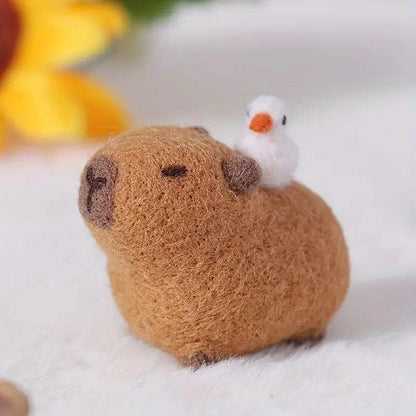 Close-up of handmade felt capybara with rounded brown body, dark muzzle and small white bird.