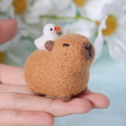 Small wool-felt capybara with white bird balanced on an open hand to show its size.
