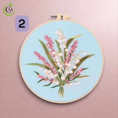Floral embroidery design two with pink and white flowers on pale blue fabric in bamboo hoop.