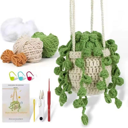 Finished cream hanging crochet plant with trailing green leaves next to yarn, scissors, hook and instructions.