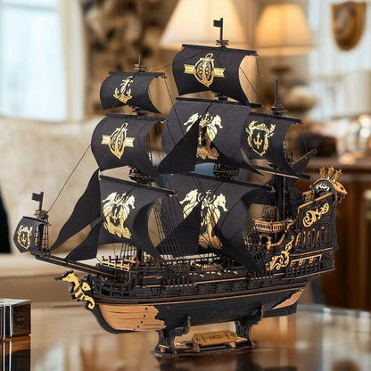 Completed Seahorse Barque wooden pirate ship with black sails and gold seahorse decoration on wooden table.